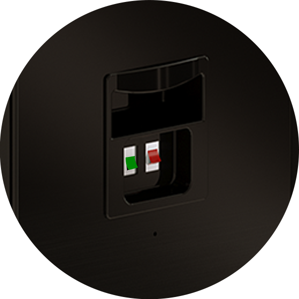 Close-up of a speaker’s rear panel showing two spring-clip terminals, one with a red tab and one with a green tab, for connecting speaker wires. The panel is set into a black surface.